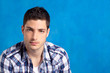 handsome young man with plaid shirt on blue