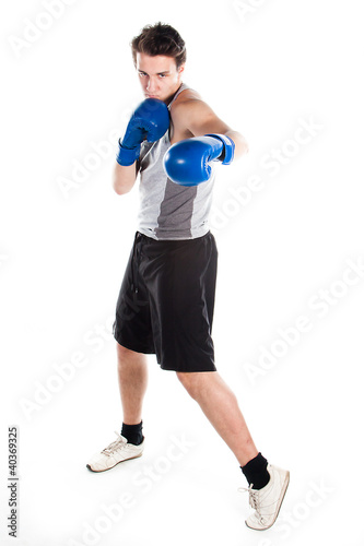 Photo: young boxer in gray shirt and blue boxing gloves young boxer in gray shirt and blue boxing gloves