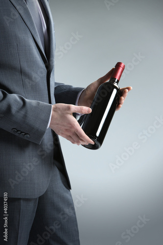 Photo: elegant man holding a bottle with a red wine elegant man holding a bottle with a red wine
