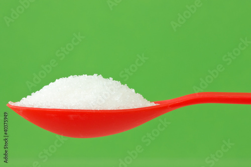 Photo: spoon with sugar on green background spoon with sugar on green background