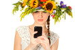 Foto: Beautiful girl with hat of flowers and phone in her hands Beautiful girl with hat of flowers and phone in her hands