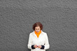 Photo: Frau an Mauer mit Smartphone Frau an Mauer mit Smartphone