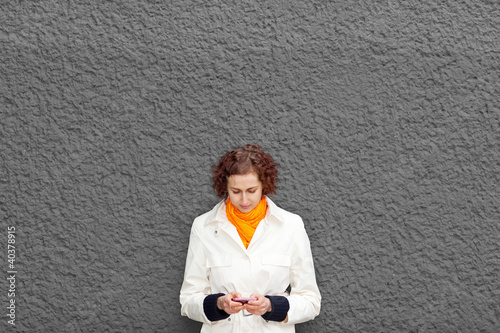 Photo: Frau an Mauer mit Smartphone Frau an Mauer mit Smartphone
