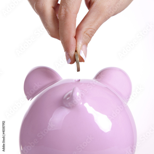 Photo: Woman putting a coin in a piggy bank Woman putting a coin in a piggy bank
