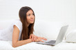 Young succesful woman lying on a sofa with laptop