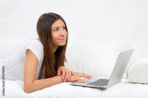 Photo: Young succesful woman lying on a sofa with laptop Young succesful woman lying on a sofa with laptop