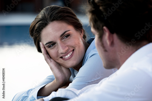 Photo: Young couple relaxing by pool Young couple relaxing by pool