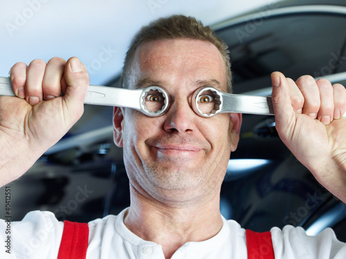 Photo: Ridiculous motor mechanic in a garage has a lot of fun at work Ridiculous motor mechanic in a garage has a lot of fun at work