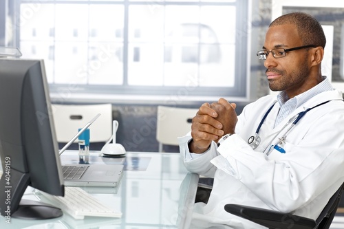 Photo: Troubled doctor sitting at desk Troubled doctor sitting at desk