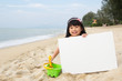 Little child girl holds a white board at beach
