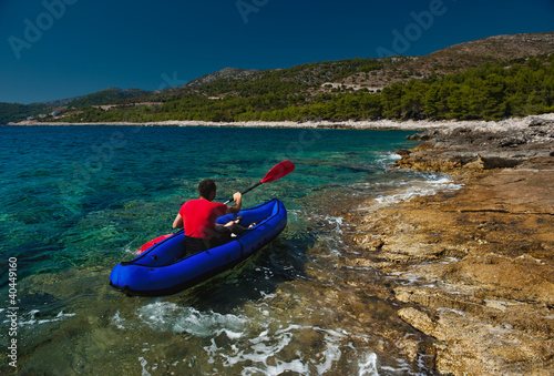 Photo: Man rowing in inflatable kayak at Adriatic sea. Hvar, Croatia Man rowing in inflatable kayak at Adriatic sea. Hvar, Croatia