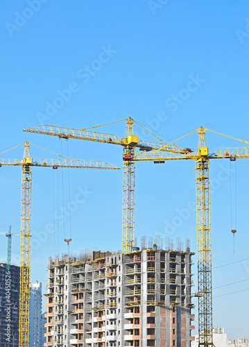 Foto: Building crane and building under construction against blue sky Building crane and building under construction against blue sky