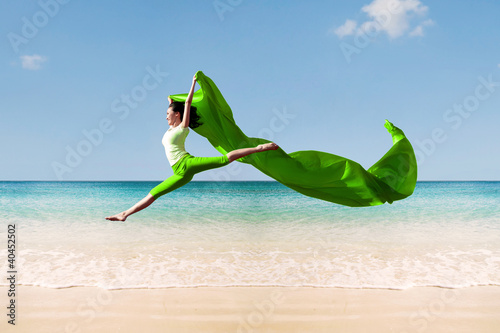 Photo: Carefree woman jumping on beach Carefree woman jumping on beach