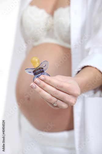 Photo: Pregnant woman holding a pacifier Pregnant woman holding a pacifier
