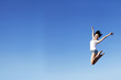 Joyful woman jumping over clear blue sky