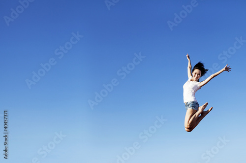 Photo: Joyful woman jumping over clear blue sky Joyful woman jumping over clear blue sky