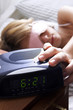 Photo: A woman sleeping with her eyes covered turning off the alarm clock. A woman sleeping with her eyes covered turning off the alarm clock.