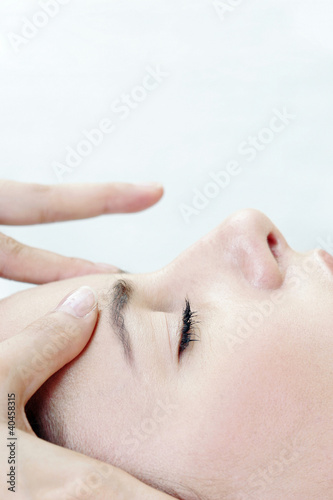 Foto: Side view of hands massaging a lady's forehead. Side view of hands massaging a lady's forehead.