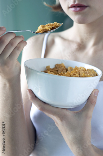 Photo: A woman in white camisole eating her breakfast cereal. A woman in white camisole eating her breakfast cereal.