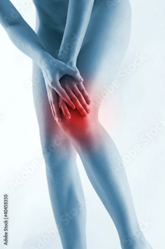 Photo: Waist down shot of a naked woman touching her aching knee. Waist down shot of a naked woman touching her aching knee.