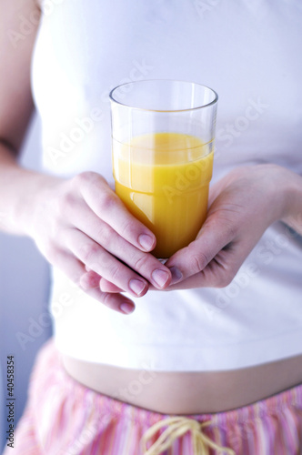 Photo: A woman holding a glass of orange juice. A woman holding a glass of orange juice.