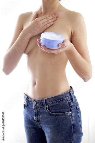 Photo: Shoulder down shot of a topless woman in jeans applying cream on her body. Shoulder down shot of a topless woman in jeans applying cream on her body.