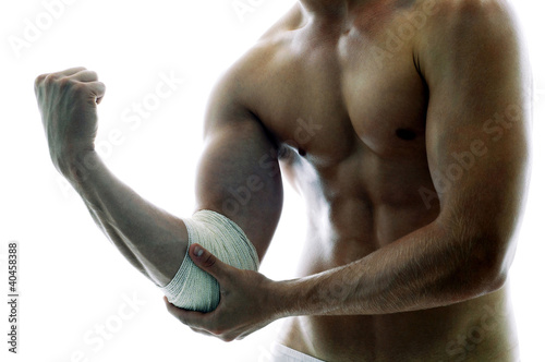 Photo: A shirtless muscular man with a bandage on his elbow. A shirtless muscular man with a bandage on his elbow.