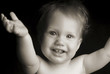 A baby with arms wide opened smiling at the camera.