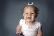 A young girl with white ribbon smiling showing off her two front teeth.