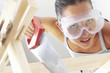 Close-up of a woman with goggles sawing a wood.