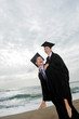 A guy and his girlfriend rejoicing their graduation by giving her a piggy back ride.