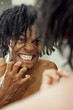 A african american guy checking his teeth on the mirror.