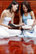 Two ladies sitting on the floor doing revision together.