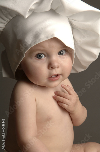 Foto: A baby with chef hat looking at the camera. A baby with chef hat looking at the camera.