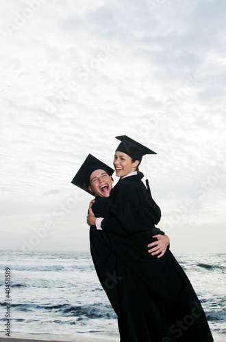 Photo: An elated guy and lady in a robe and mortar board rejoicing their graduation on the beach. An elated guy and lady in a robe and mortar board rejoicing their graduation on the beach.