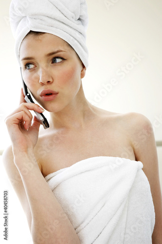 Photo: A woman with her hair and body wrapped up in towel talking on the handphone. A woman with her hair and body wrapped up in towel talking on the handphone.
