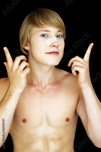 Foto: A shirtless man sticking a plaster on his nose bridge. A shirtless man sticking a plaster on his nose bridge.