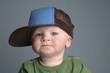 a baby boy wearing a big cap.