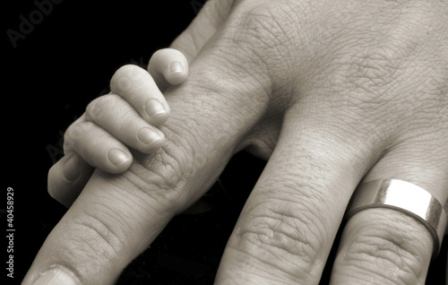 Photo: a baby's hand touching an adult's hand. a baby's hand touching an adult's hand.