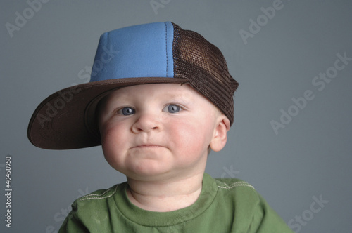 Photo: a baby boy wearing a big cap. a baby boy wearing a big cap.