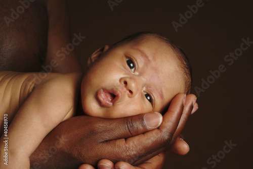 Photo: a baby lying on an adult's palm. a baby lying on an adult's palm.