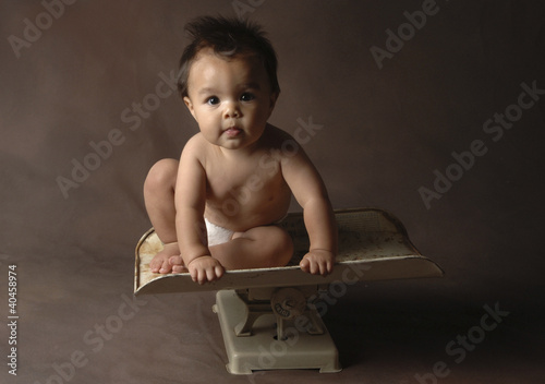 Photo: a young boy sitting on a weighing machine. a young boy sitting on a weighing machine.