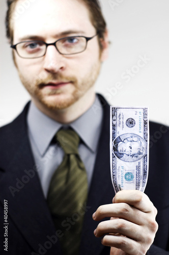Photo: a bespectacled man in business suit holding a banknote. a bespectacled man in business suit holding a banknote.