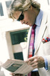 A guy in business suit and sunglass reading newspaper.