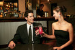 A couple in dinner wear having a toast in the bar.
