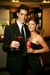 A couple in dinner wear standing together holding cocktails.
