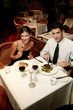 A couple in dinner wear celebrating their anniversary by eating in the restaurant.
