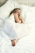 a girl hugging a teddy bear on the bed.