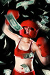 A swollen faced lady in a boxing suit and protective gear acting crazy with bank notes flying in the air.