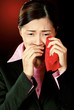 A lady in formal suit wiping her tears with a red handkerchief.